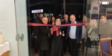 Στην έκθεση φωτογραφίας Γρεβενών, ο Μητροπολίτης Γρεβενών και ο Δήμαρχος κόβουν την κορδέλα στα εγκαίνια, με πλήθος κόσμου να παρακολουθεί.