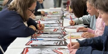 Μαθητές συγκεντρώνονται γύρω από ένα μεγάλο τραπέζι και ζωγραφίζουν σε ένα εργαστήριο για την Ψυχική Υγεία στη Φλώρινα.