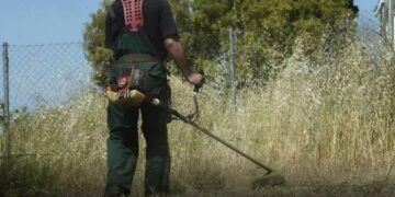 Ένας εργάτης χρησιμοποιεί ένα βενζινοκίνητο χορτοκοπτικό για τον καθαρισμό ενός οικοπέδου στη Φλώρινα, προετοιμάζοντας το για την αντιπυρική περίοδο 2026.