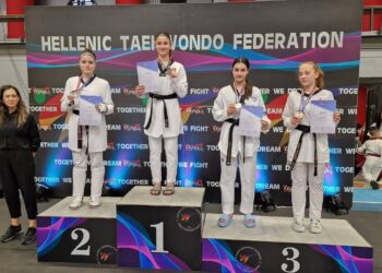 Τρεις αθλήτριες της Μακεδονικής Δύναμης Κοζάνης στέκονται στο βάθρο των νικητών στο Πανελλήνιο Κύπελλο Ταεκβοντό, φορώντας τις στολές τους και τα μετάλλιά τους.