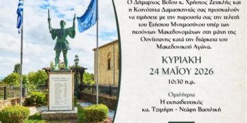 Ένα άγαλμα ενός Μακεδονομάχου στέκεται μπροστά από ένα μνημείο στο χωριό Δαμασκηνιά, ενώ γύρω του υπάρχουν σημαίες και ένα όμορφο τοπίο, τιμώντας το μνημόσυνο μακεδονομάχων.