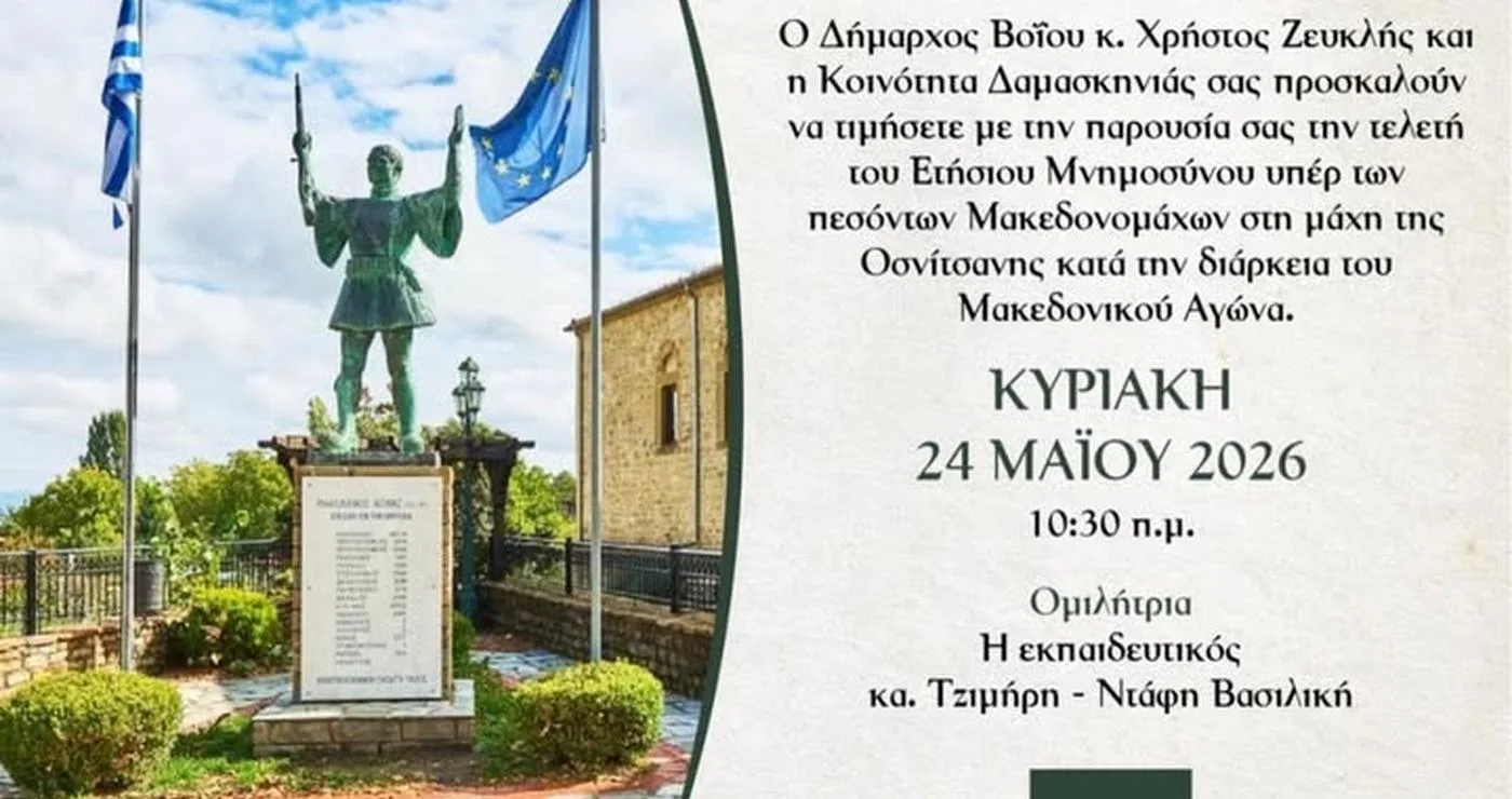 Ένα άγαλμα ενός Μακεδονομάχου στέκεται μπροστά από ένα μνημείο στο χωριό Δαμασκηνιά, ενώ γύρω του υπάρχουν σημαίες και ένα όμορφο τοπίο, τιμώντας το μνημόσυνο μακεδονομάχων.