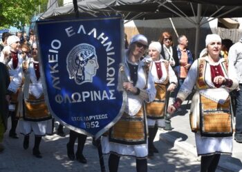 Μια ομάδα χορευτών του Λυκείου Ελληνίδων Φλώρινας περπατάει σε μια παραποτάμια περιοχή κατά τη διάρκεια της γιορτής του Χορός στη Φλώρινα.