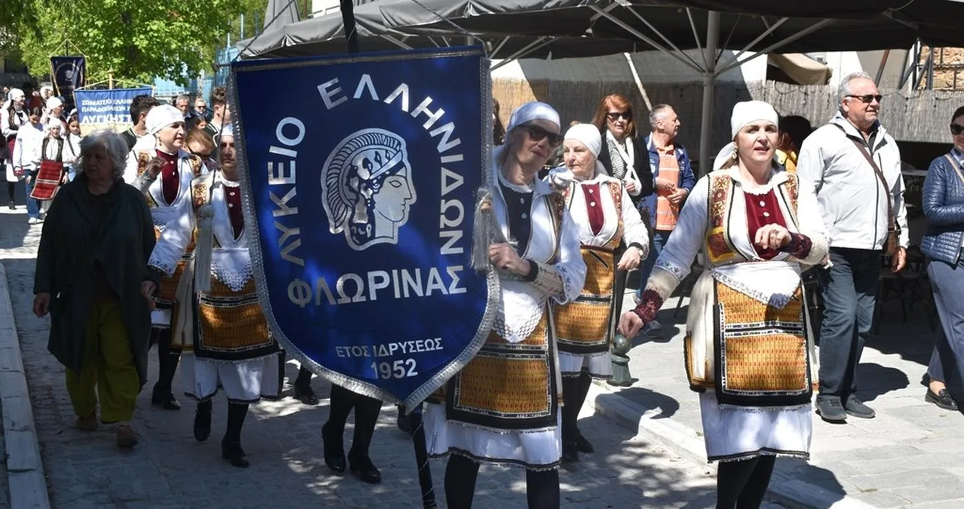 Μια ομάδα χορευτών του Λυκείου Ελληνίδων Φλώρινας περπατάει σε μια παραποτάμια περιοχή κατά τη διάρκεια της γιορτής του Χορός στη Φλώρινα.