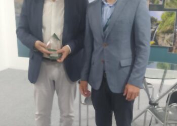 Δύο άνδρες, ο Δήμαρχος Φλώρινας και ο προϊστάμενος της Διεύθυνσης Κοινωνικής Προστασίας, χαμογελούν και κρατούν το βραβείο καινοτομίας για τον Δήμο Φλώρινας.