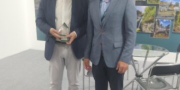 Δύο άνδρες, ο Δήμαρχος Φλώρινας και ο προϊστάμενος της Διεύθυνσης Κοινωνικής Προστασίας, χαμογελούν και κρατούν το βραβείο καινοτομίας για τον Δήμο Φλώρινας.
