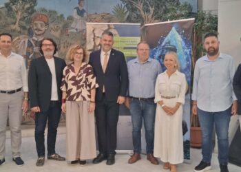 Μια ομάδα ανθρώπων στέκεται μπροστά από έναν τοίχο με μια τοιχογραφία, αντιπροσωπεύοντας τον δήμο Φλώρινας και τα ποτάμια της περιοχής.