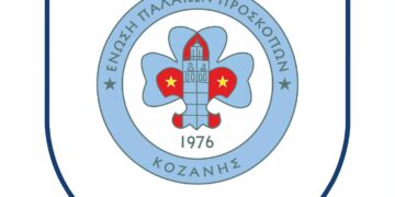 Το λογότυπο της Ένωσης Παλαιών Προσκόπων Κοζάνης, με ένα μπλε σήμα που περιέχει ένα προσκοπικό παραστάδικο και τον αριθμό 1976, συμβολίζοντας τα 50 χρόνια των παλαιών προσκόπων κοζάνης.