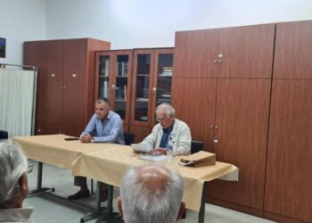 Ο ιστορικός Απόστολος Παπαδημητρίου παρουσιάζει την μάχη Σπηλαίου Γρεβενών σε ένα πλήθος ανθρώπων σε μια αίθουσα με ξύλινα ντουλάπια.