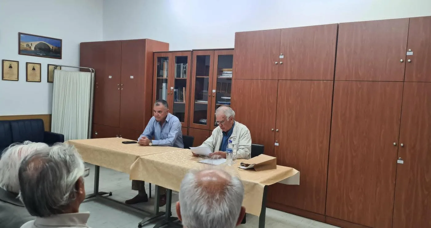Ο ιστορικός Απόστολος Παπαδημητρίου παρουσιάζει την μάχη Σπηλαίου Γρεβενών σε ένα πλήθος ανθρώπων σε μια αίθουσα με ξύλινα ντουλάπια.