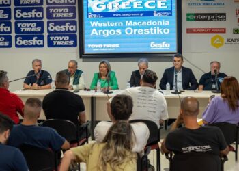 A group of people sit at a long table during a press conference for Baja Greece 2026 in Western Macedonia, with logos of sponsors and the region displayed on a backdrop.