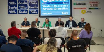 A group of people sit at a long table during a press conference for Baja Greece 2026 in Western Macedonia, with logos of sponsors and the region displayed on a backdrop.