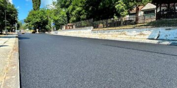 Μια καινούργια ασφαλτοστρωμένη οδός στην Φλώρινα, με πράσινο φόντο και έναν καθαρό μπλε ουρανό, αποτελεί μέρος των εργασιών ασφαλτοστρώσεων Φλώρινας.