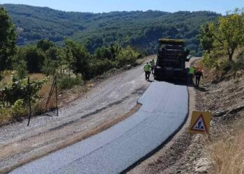 Η οδοποιία Βοΐου προχωράει, με μια νέα ασφαλτοστρωμένη οδική αρτηρία να διασχίζει ένα καταπράσινο τοπίο με λόφους και δέντρα.