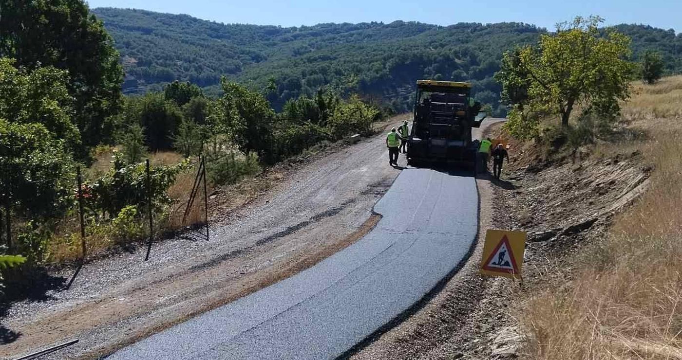Η οδοποιία Βοΐου προχωράει, με μια νέα ασφαλτοστρωμένη οδική αρτηρία να διασχίζει ένα καταπράσινο τοπίο με λόφους και δέντρα.