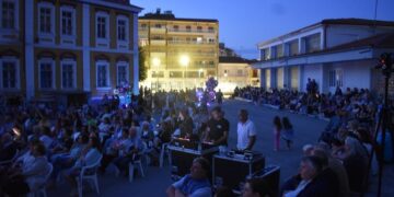 Ένα μεγάλο πλήθος κόσμου παρακολουθεί τη συναυλία των ΦλωριΝότες Φλώρινα στον αύλειο χώρο των Δημοτικών Σχολείων, σε μια όμορφη καλοκαιρινή βραδιά.