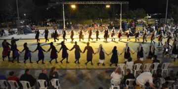Χορευτές σχηματίζουν έναν μεγάλο κύκλο χορεύοντας στο Νέο Πάρκο της Φλώρινας κατά τη διάρκεια του Πολιτιστικού Καλοκαιριού 2026.