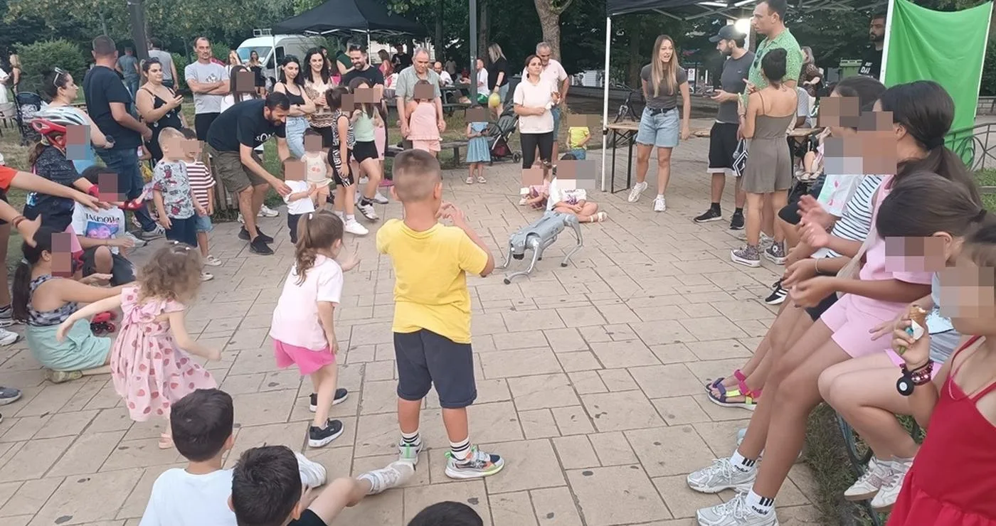 Μια ομάδα παιδιά συμμετέχει με ενθουσιασμό στο παιδικό φεστιβάλ Φλώρινας, χορεύοντας σε έναν κυκλικό χώρο στο Νέο Πάρκο.