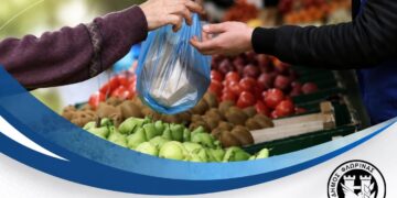 Ένα χέρι παραδίδει λαχανικά σε μια πλαστική σακούλα στην λαϊκή αγορά Φλώρινας.