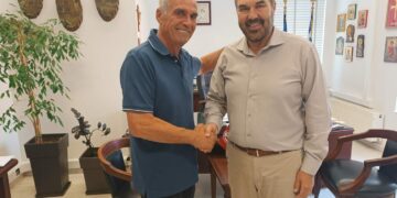 Δύο άνδρες ανταλλάσσουν χειραψία σε γραφείο, ο ένας εκ των οποίων είναι ο νέος αντιδήμαρχος Φλώρινας.