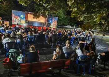 Ένα πλήθος θεατών παρακολουθεί με ενθουσιασμό μια παράσταση Θεάτρου Σκιών Λεβαία σε μια καλοκαιρινή βραδιά.