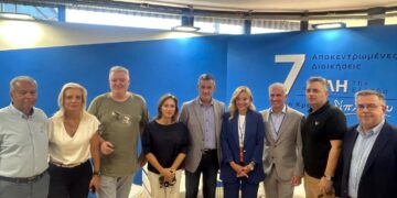 Έξι άτομα, οι Γραμματείς των Αποκεντρωμένων Διοικήσεων, στέκονται χαμογελαστοί στο περίπτερο των Αποκεντρωμένων Διοικήσεων στη ΔΕΘ.