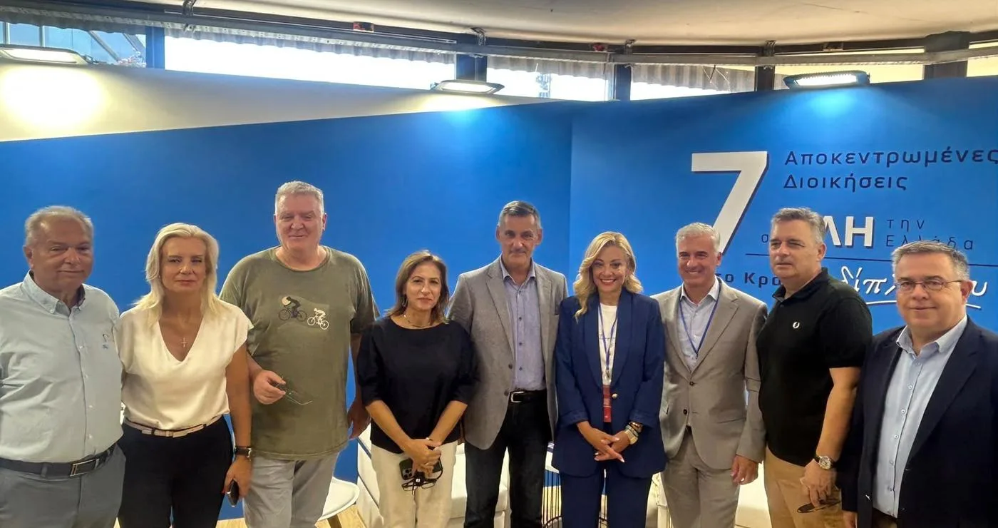 Έξι άτομα, οι Γραμματείς των Αποκεντρωμένων Διοικήσεων, στέκονται χαμογελαστοί στο περίπτερο των Αποκεντρωμένων Διοικήσεων στη ΔΕΘ.