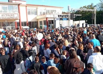 A large crowd of people gathers in front of the building hosting the Εμποροβιοτεχνική Έκθεση Δυτικής Μακεδονίας.