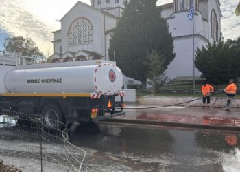 Ένα λευκό βυτιοφόρο του Δήμου Φλώρινας πλένει την πλατεία Αμυνταίου μετά την Εμποροπανήγυρη, με φόντο τον καθεδρικό ναό και την ελληνική σημαία, ως μέρος του καθαρισμού Αμυνταίου.