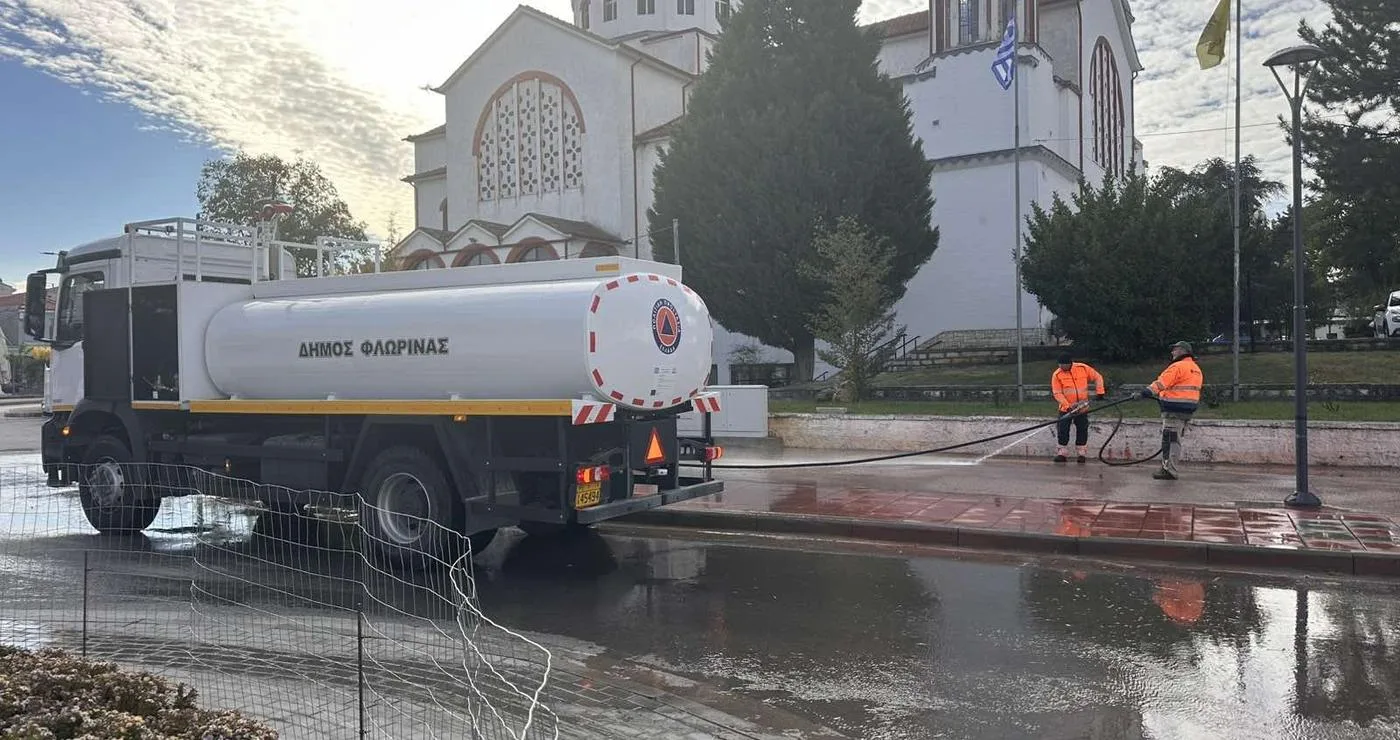 Ένα λευκό βυτιοφόρο του Δήμου Φλώρινας πλένει την πλατεία Αμυνταίου μετά την Εμποροπανήγυρη, με φόντο τον καθεδρικό ναό και την ελληνική σημαία, ως μέρος του καθαρισμού Αμυνταίου.