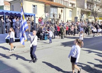 Μαθητές κρατούν την ελληνική σημαία και περπατούν σε μια παρέλαση για τον εορτασμό της απελευθέρωσης των Γρεβενών.