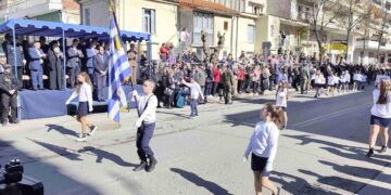 Μαθητές κρατούν την ελληνική σημαία και περπατούν σε μια παρέλαση για τον εορτασμό της απελευθέρωσης των Γρεβενών.