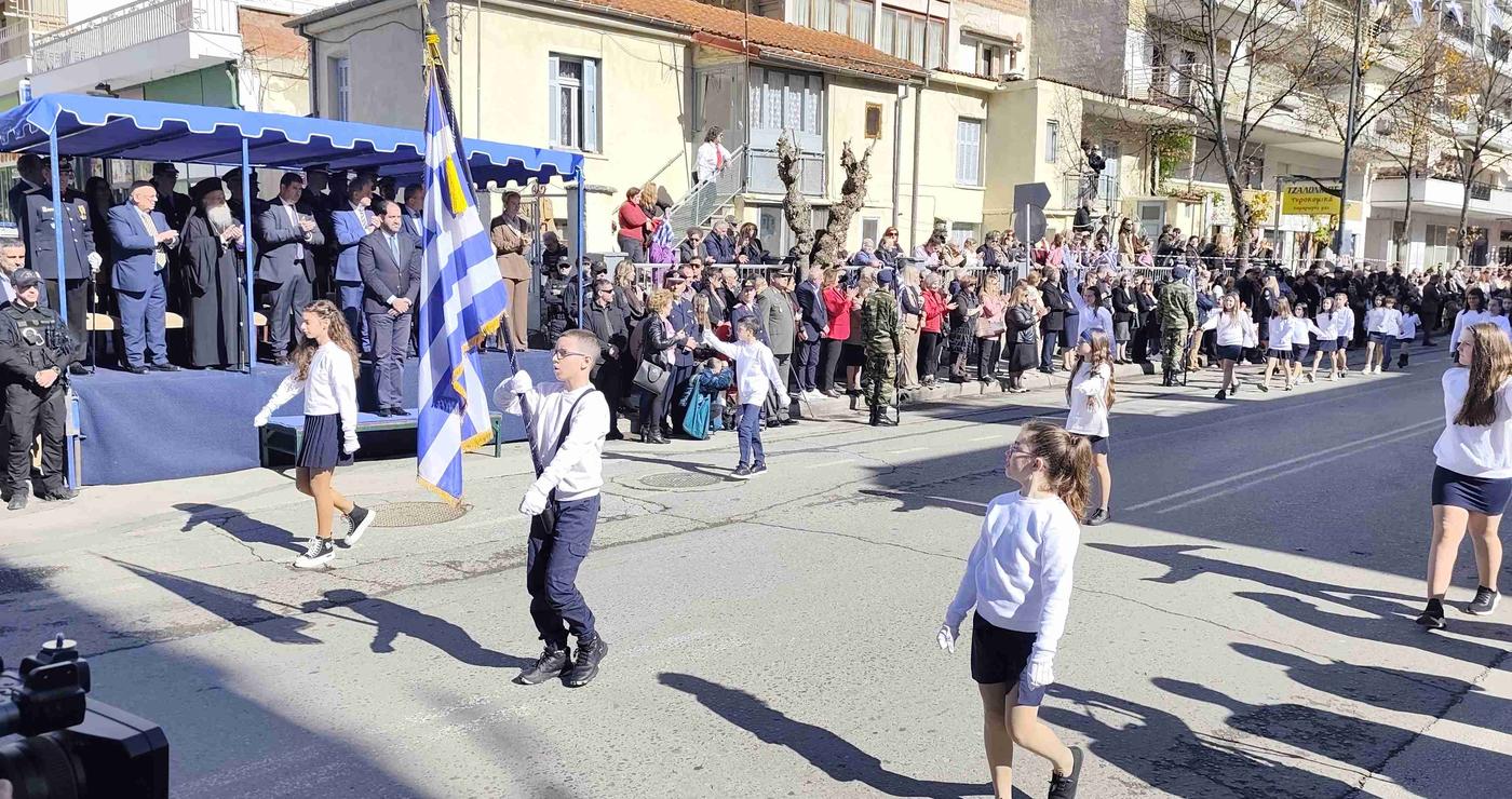 Μαθητές κρατούν την ελληνική σημαία και περπατούν σε μια παρέλαση για τον εορτασμό της απελευθέρωσης των Γρεβενών.