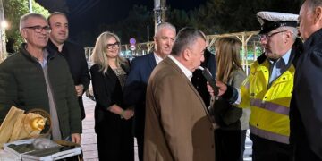 Μια ομάδα ανθρώπων στέκεται έξω από ένα wine-resto-bar στο Αμύνταιο, συμμετέχοντας στην «Ευρωπαϊκή Νύχτα χωρίς Ατυχήματα» και συζητώντας με έναν αστυνομικό.