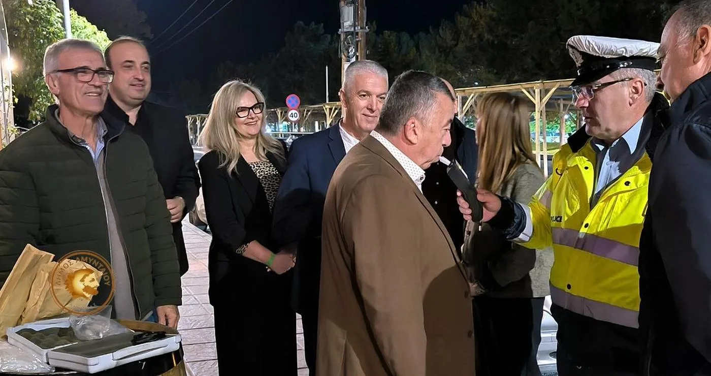 Μια ομάδα ανθρώπων στέκεται έξω από ένα wine-resto-bar στο Αμύνταιο, συμμετέχοντας στην «Ευρωπαϊκή Νύχτα χωρίς Ατυχήματα» και συζητώντας με έναν αστυνομικό.