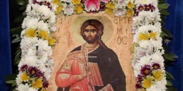 Η εικόνα του Αγίου Αρτεμίου, προστάτη της ελληνικής αστυνομίας, περιτριγυρισμένη από λουλούδια σε εορταστικό πλαίσιο.